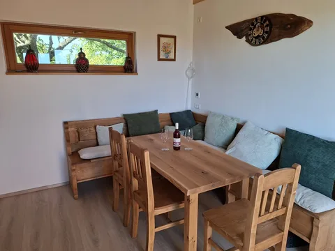 Esstisch mit Eckbank, zwei Weingläsern und einer Flasche Wein
