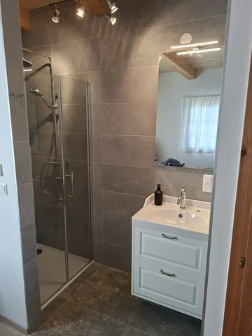 Badezimmer mit bodengleicher Dusche, großem Spiegel und Waschbecken